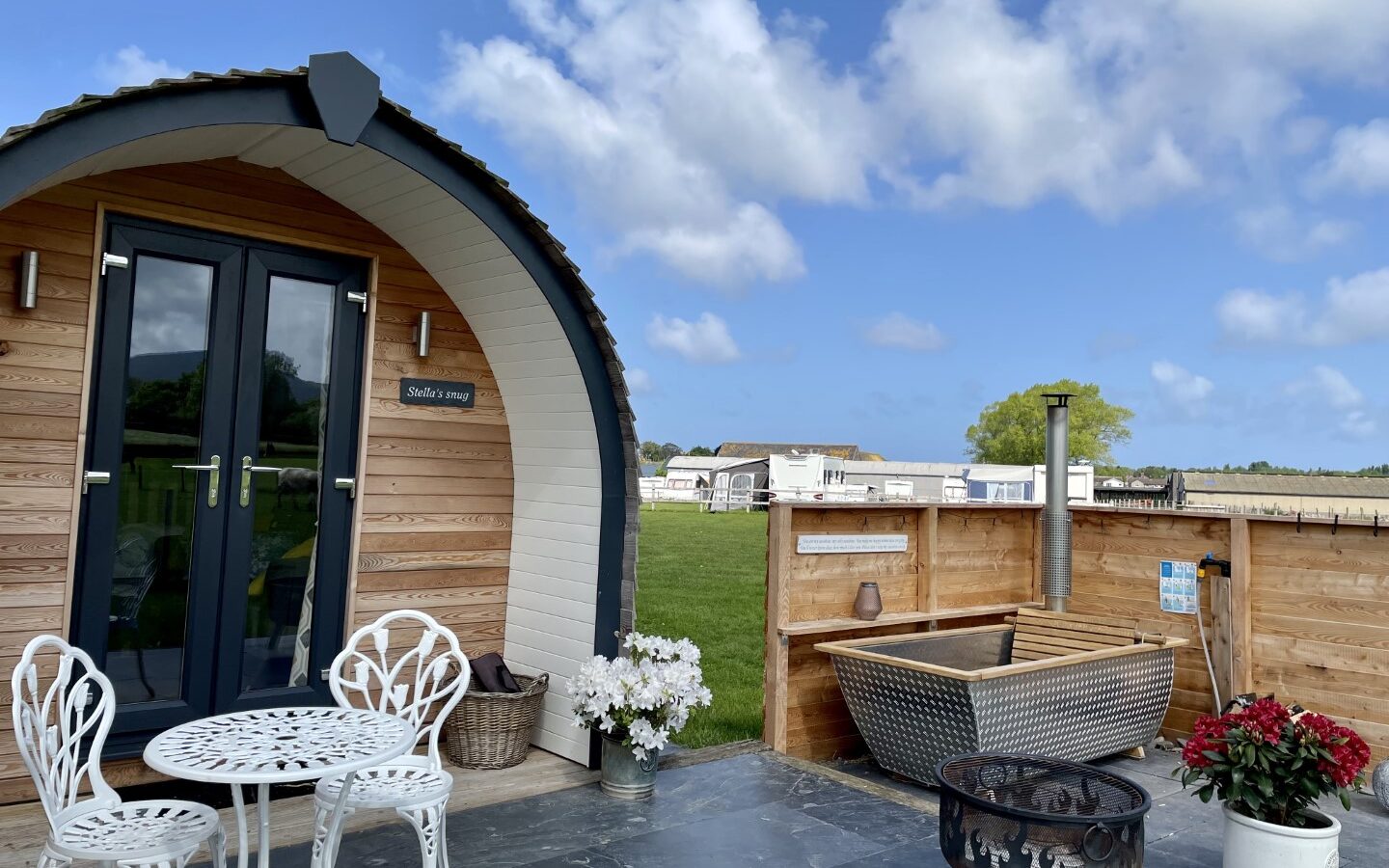 A cozy wooden cabin with an arched roof and a sign saying 