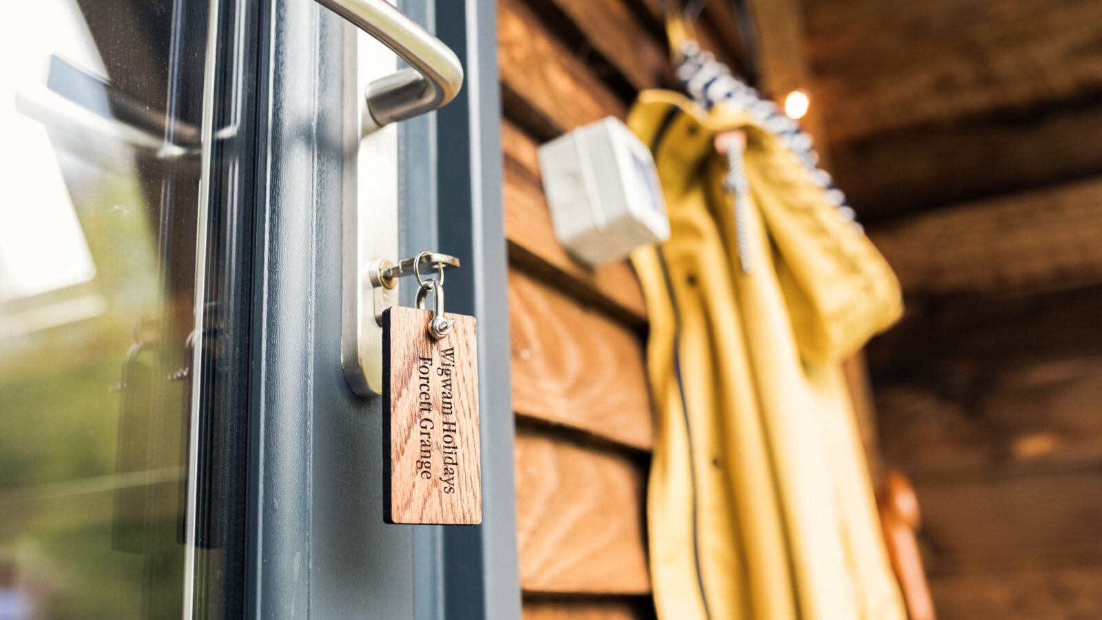 Close-up of a door handle with a wooden keychain engraved 