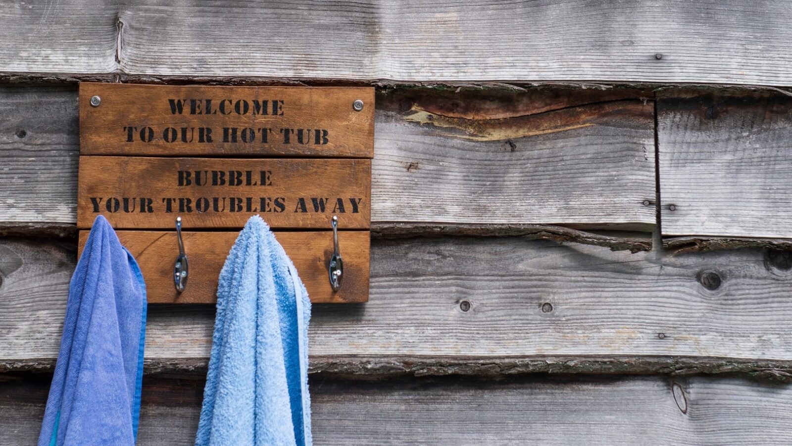 A rustic wooden sign on a weathered wooden wall reads 